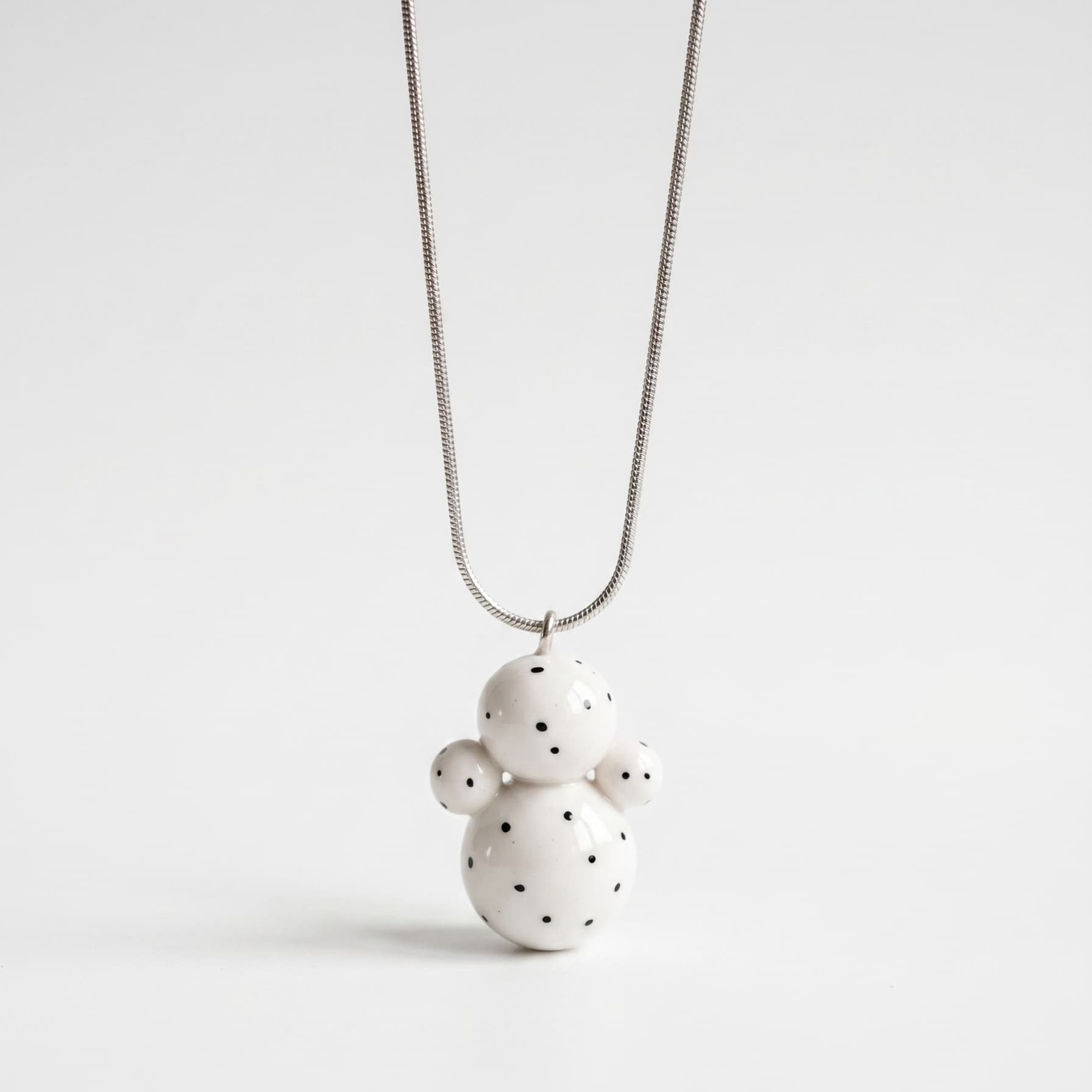 Necklace with a white ceramic pendant on a light gray background