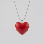 Red heart-shaped pendant on a chain against a light gray background