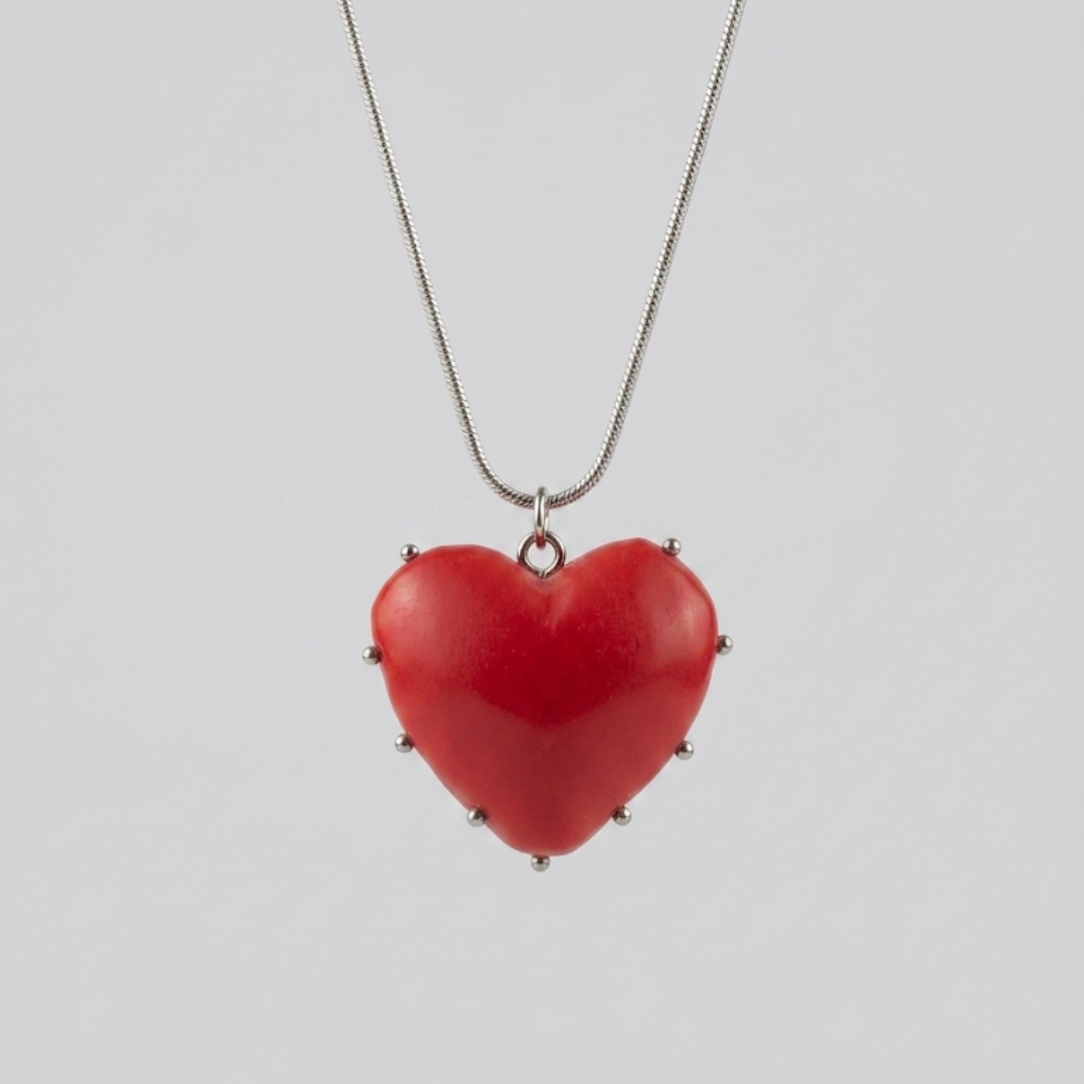 Red heart-shaped pendant on a chain against a light gray background