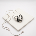 Necklace with a zebra-striped heart pendant on a white surface