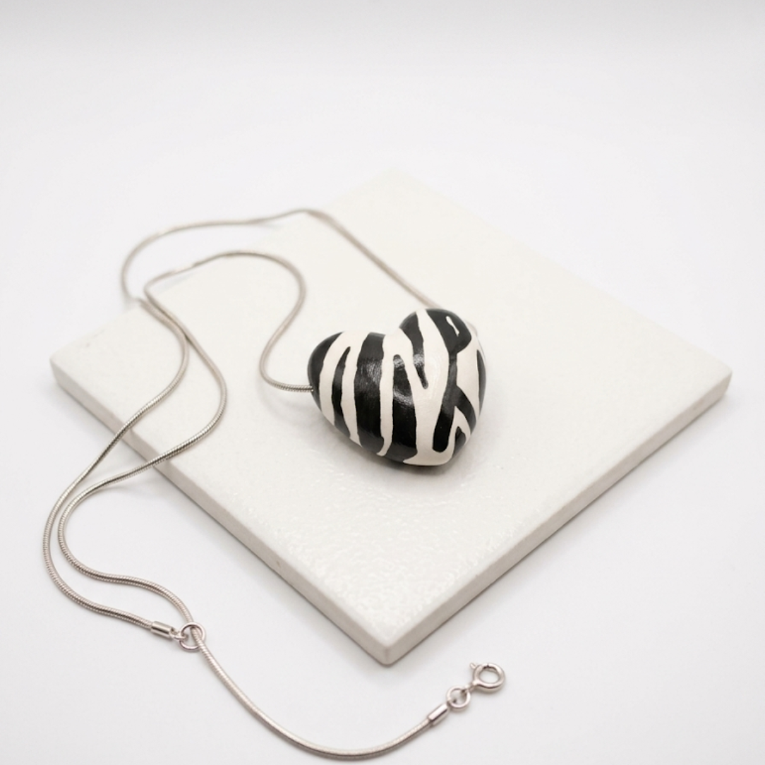 Necklace with a zebra-striped heart pendant on a white surface
