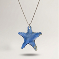 Blue star-shaped pendant on a chain against a light gray background